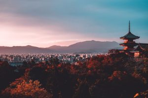 Sunset view of Kyoto with Kiyomizu-dera temple and mountains, capturing the cultural beauty of Japan.