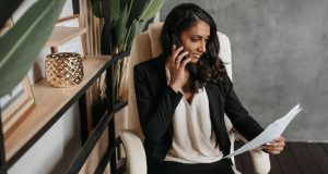Woman reviewing documents while on a phone call in stylish office setting.